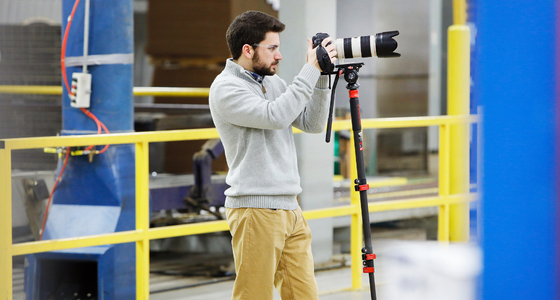Camera operator filming on a factory floor