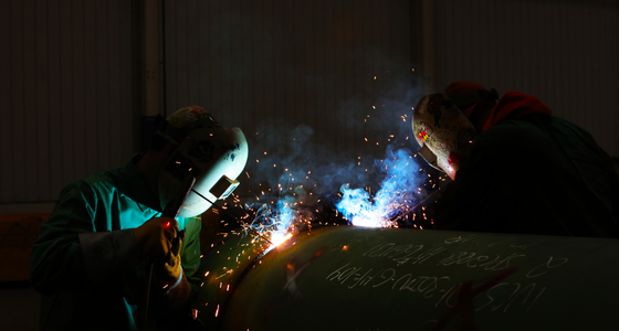 Two welders at work under sparks, filmed for an industrial brand film