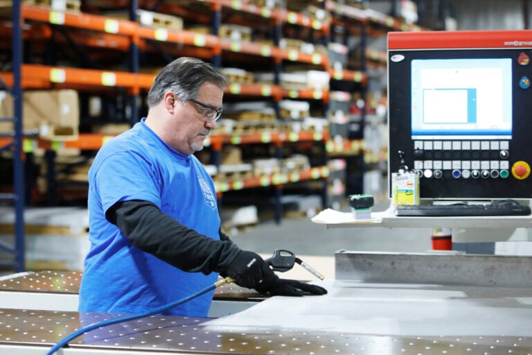 A Piedmont Plastics operator at a cutting table and control panel, from the Piedmont Plastics case study