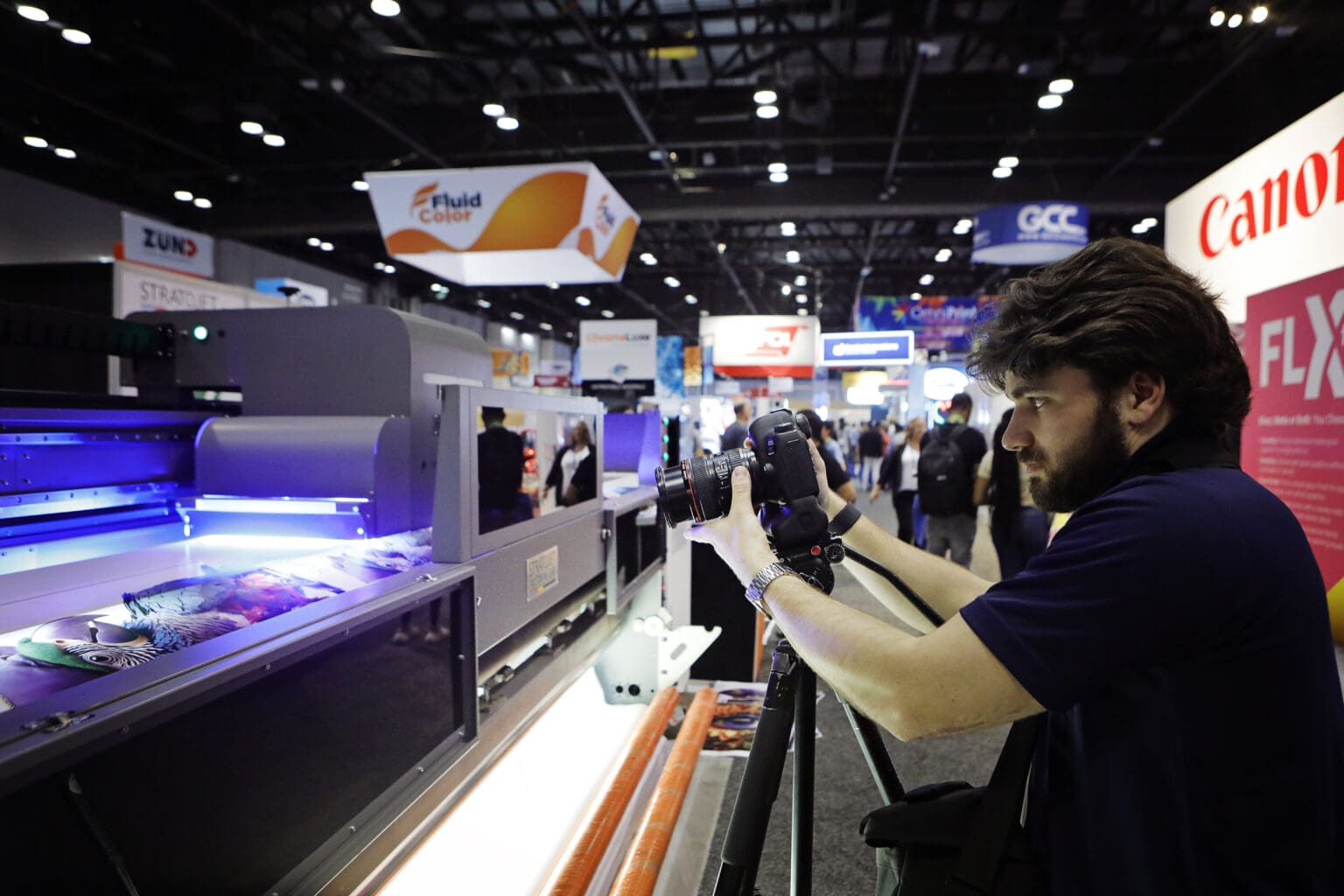 A Howell Studios camera operator films a wide-format UV printer on the show floor at ISA International Sign Expo in Orlando